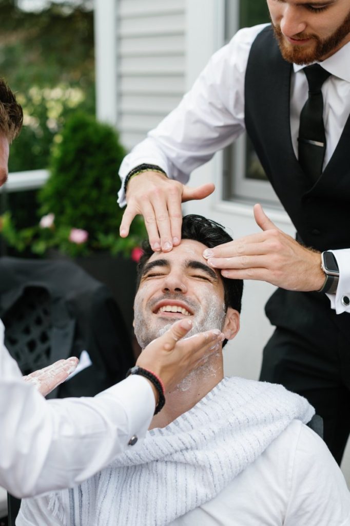 Groom getting shaved on wedding day at Henry Hotel, Dearborn